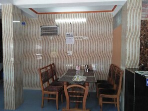 A small, enclosed dining area with a striped wall, a table, four chairs, and a sign prohibiting drinking. - Galaxy Hotel (Lansdowne)