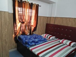 A bedroom with a wooden headboard, a bed with striped bedding, and curtains. - Galaxy Hotel (Lansdowne)