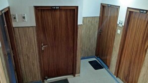Un pasillo con tres puertas de madera, cada una con un número de habitación. Hay felpudos en el suelo frente a las puertas.