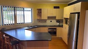 Una cocina con armarios de madera, un refrigerador de acero inoxidable, un horno empotrado y una isla grande con taburetes de bar.