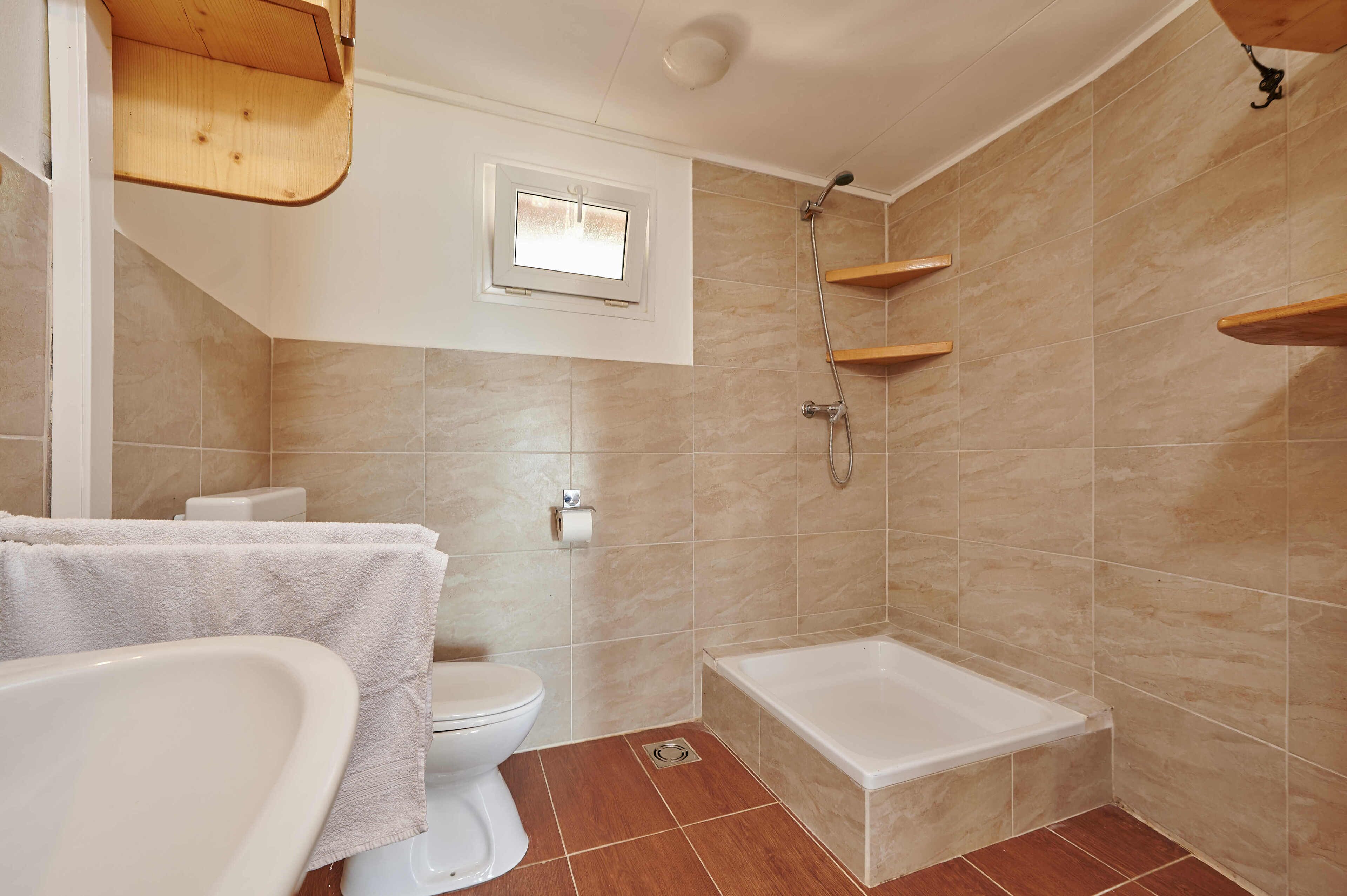A bathroom with a bathtub, toilet, and a window.