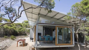 A modern house with a glass-enclosed patio, a dining area with chairs, and a small table.