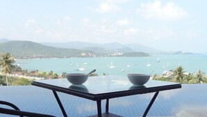 Mesa com duas tigelas, com vista para a costa, barcos e montanhas.