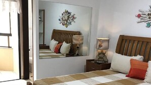 Un dormitorio con una cama de madera, una mesita de noche con lámparas, un espejo y un adorno en la pared.