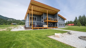Une maison à deux étages avec une terrasse en bois et un porche couvert.