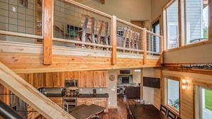Un intérieur spacieux en bois, aménagé sur plusieurs niveaux, comprenant une cuisine, un coin repas et un escalier.