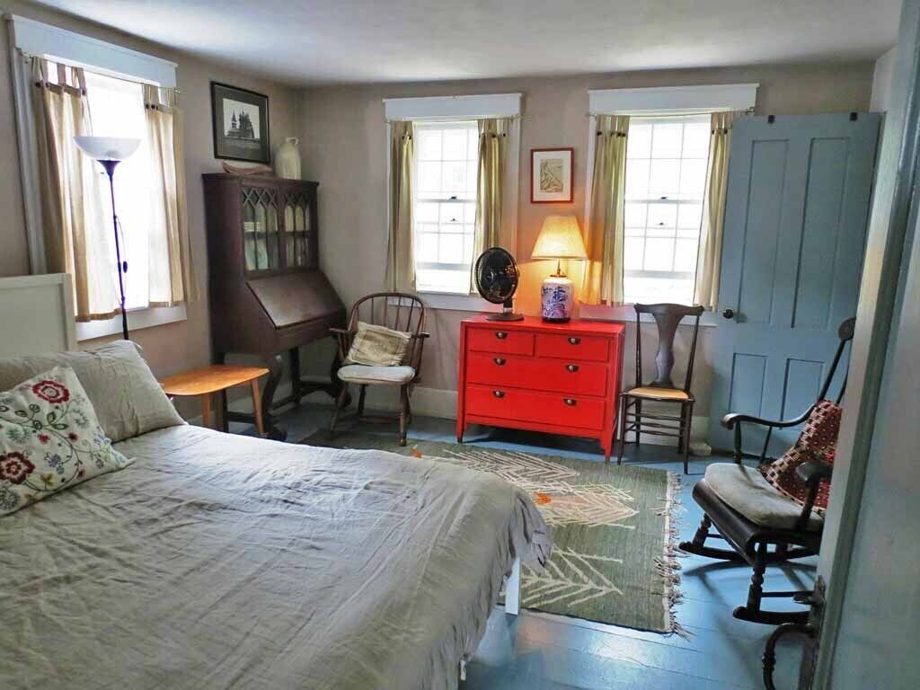 A bedroom with a bed, dresser, chairs, and a desk.
