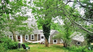 A backyard with a hammock, a chair, and a small shed.