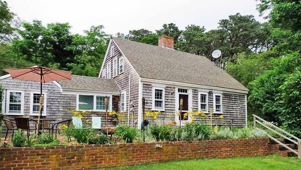 A two-story house with a brick foundation and a grassy yard.
