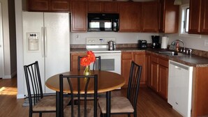 A kitchen with wooden cabinets, a white refrigerator, a microwave, a stove, and a sink.