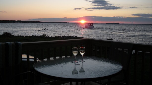 A table with two wine glasses and a view of the sunset over the water.