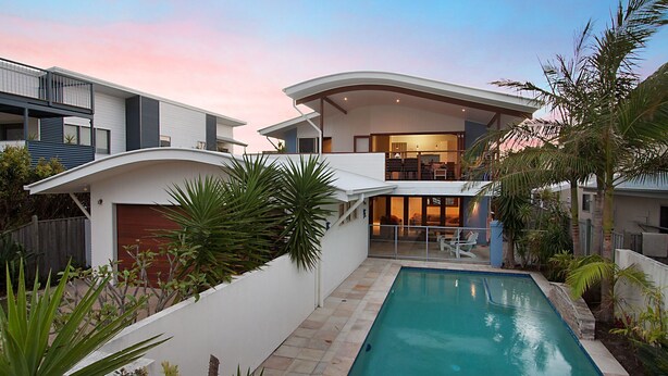 Une maison moderne à deux étages, dotée d’une piscine, d’un patio couvert et d’un grand jardin.