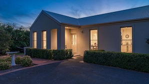 A modern two-story house with a well-lit entrance, a covered porch, and a driveway leading to the front door. - Mount Eliza Sunset Apartment (Mount Eliza)