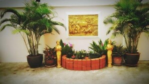 A courtyard with potted plants, a decorative brick planter, and a framed artwork on the wall.