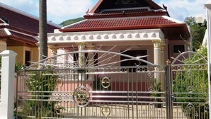 A traditional house with a red tiled roof and a decorative gate.