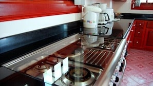 A kitchen with a gas stove, a coffee maker, and a kettle.