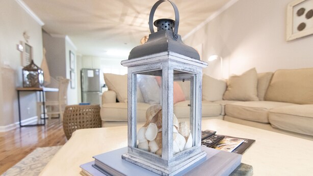 A living room with a white coffee table, a white sofa, and a decorative lantern with seashells.