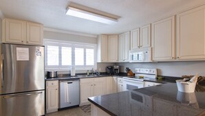A modern kitchen with white cabinets, stainless steel appliances, and a granite countertop.