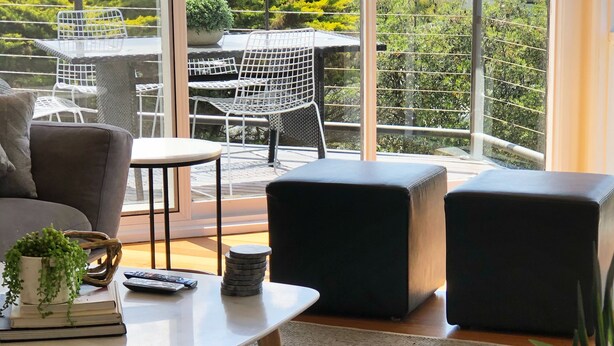 Een moderne woonkamer met een groot balkon, met een bank, een salontafel en een eethoek met stoelen.
