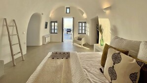 Un dormitorio amplio con una cama grande, una escalera, una silla y vistas al exterior.