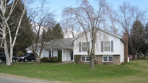 A two-story house with a front porch, a brick chimney, and a garage.