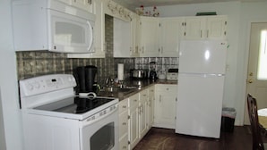 A kitchen with white cabinets, a microwave, stove, and refrigerator.
