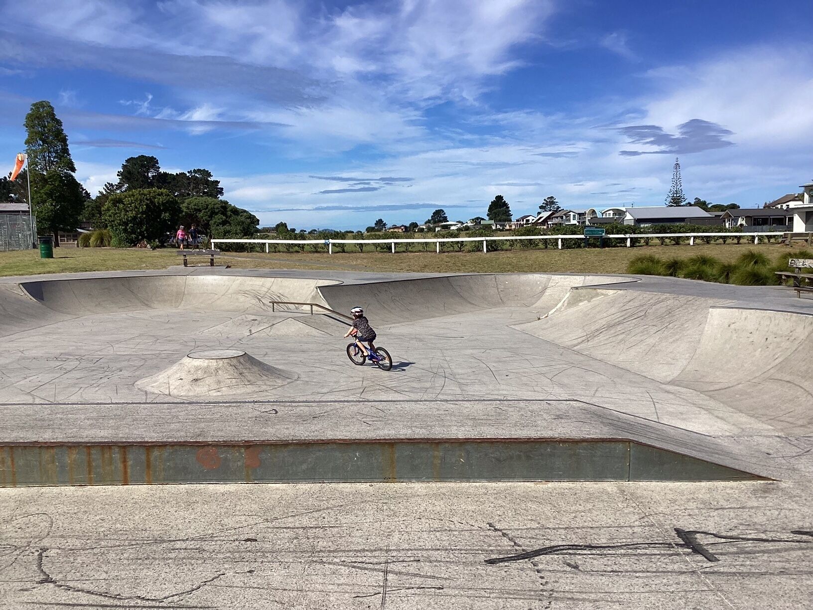 Una pista de skate con un bowl de hormigón grande y una persona montando en bicicleta.