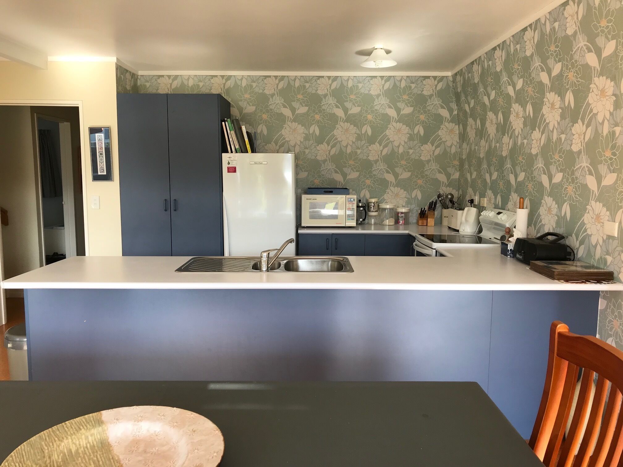 Una cocina con una isla central, un refrigerador, un microondas y un lavabo.