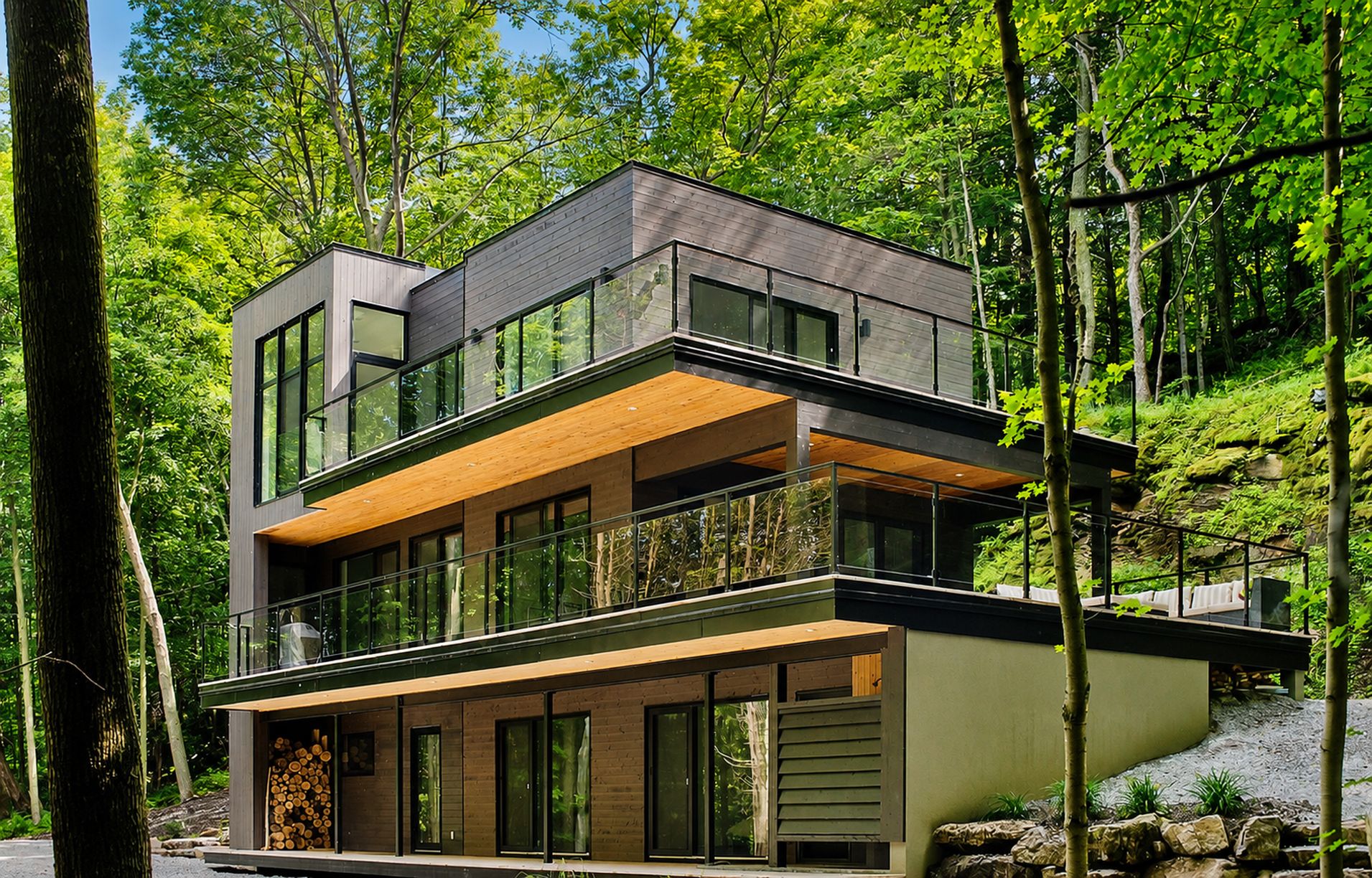 A modern multi-story house with large windows, a balcony, and a wooden deck.
