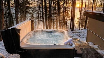 A hot tub outdoors with a view of trees and a sunset.