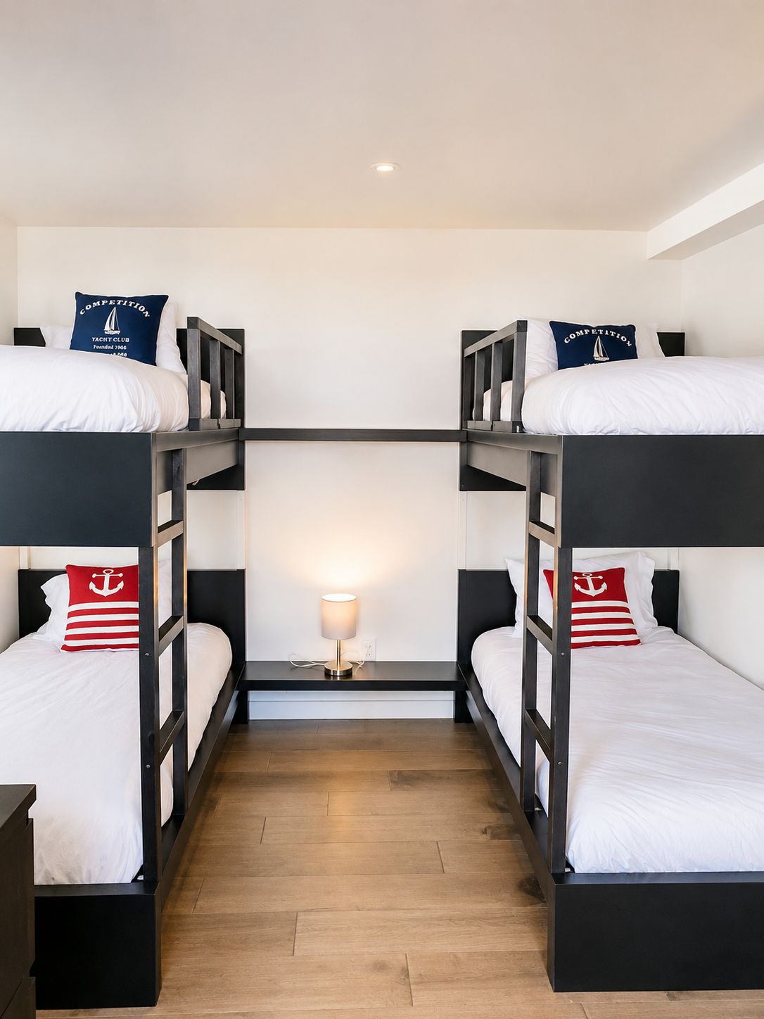 A bunk bed room with a central table and a lamp.