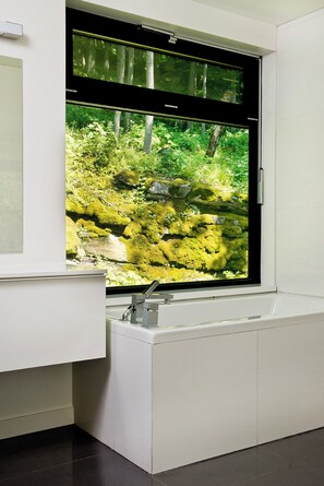 A bathroom with a window overlooking a forested area.