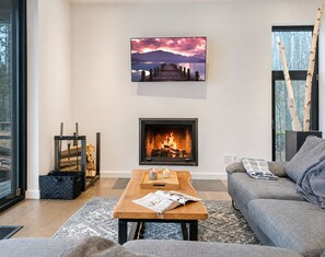 A living room with a fireplace, a sofa, a coffee table, and a painting on the wall. - Lakefront Private Oasis Hot Tub Pet Friendly (St-Armand)