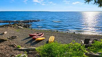 Una playa con kayaks y un litoral rocoso.