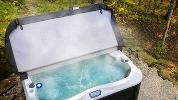 A portable hot tub in a forested area with a gravel path and trees.