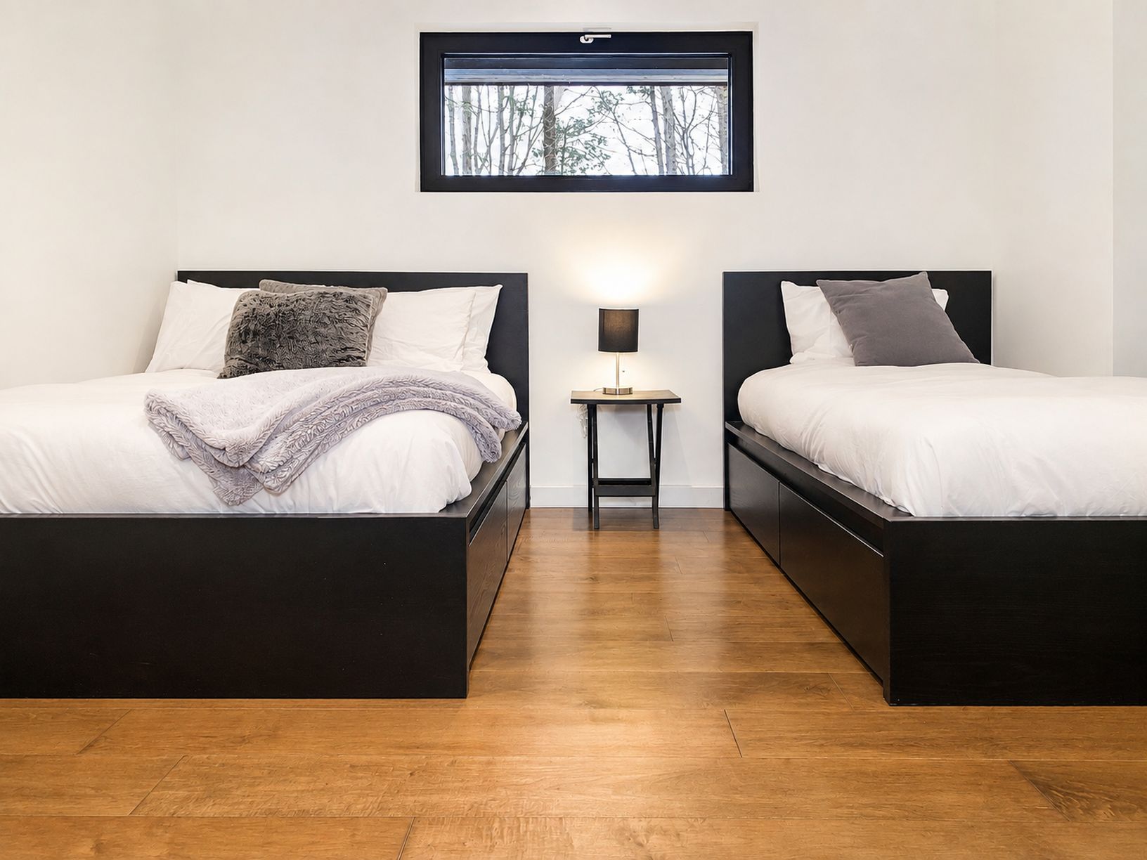 A room with two beds, a small table, and a window.