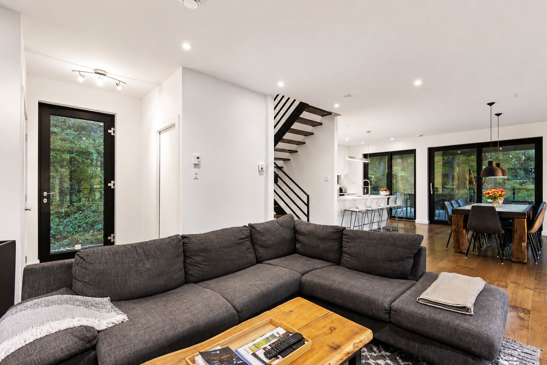 A modern living room with a sectional sofa, a wooden coffee table, and a staircase leading to an upper level.