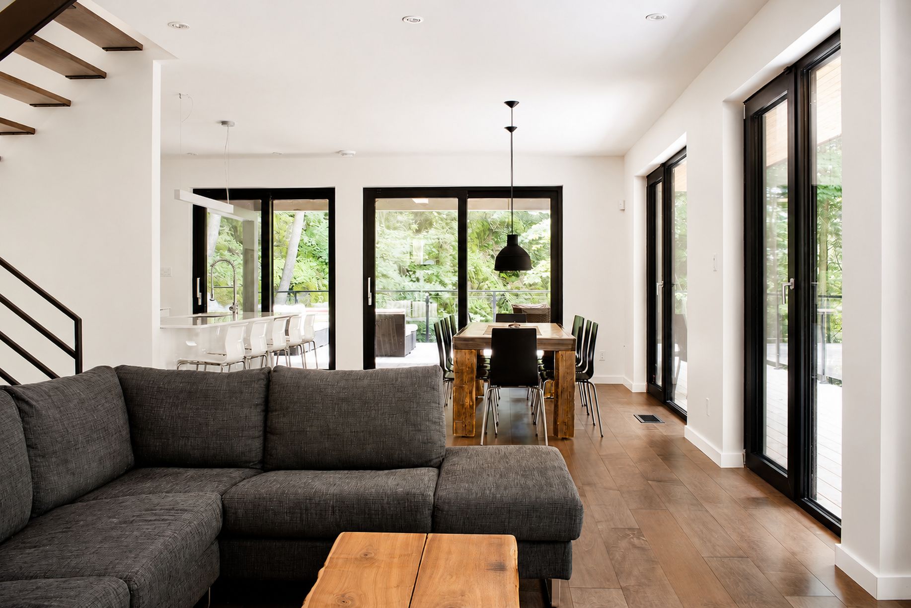 Una sala de estar moderna con un sofá seccional, una mesa de centro de madera y un comedor con mesa y sillas.