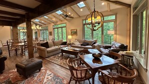 A spacious living area with a high ceiling, large windows, and a cozy seating arrangement. - Hosting a retreat, family reunion, girls or couples weekend or special occasion? (Ellijay)