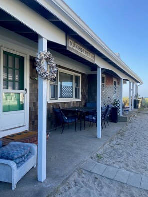A covered outdoor seating area with a table and chairs, a decorative wreath, and a sign reading "DUNEO TOOTIN".