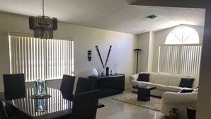 A modern living room with a dining area, featuring a chandelier, a sofa, a coffee table, and a dining table with chairs. - PERFECT RELAXING  GETAWAY FOR COUPLE OR SMALL GROUP (Boynton Beach)