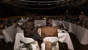 A wedding ceremony with guests seated at round tables, decorated with flowers and candles. - Whitebird Summit 7 bedroom home (Grangeville)