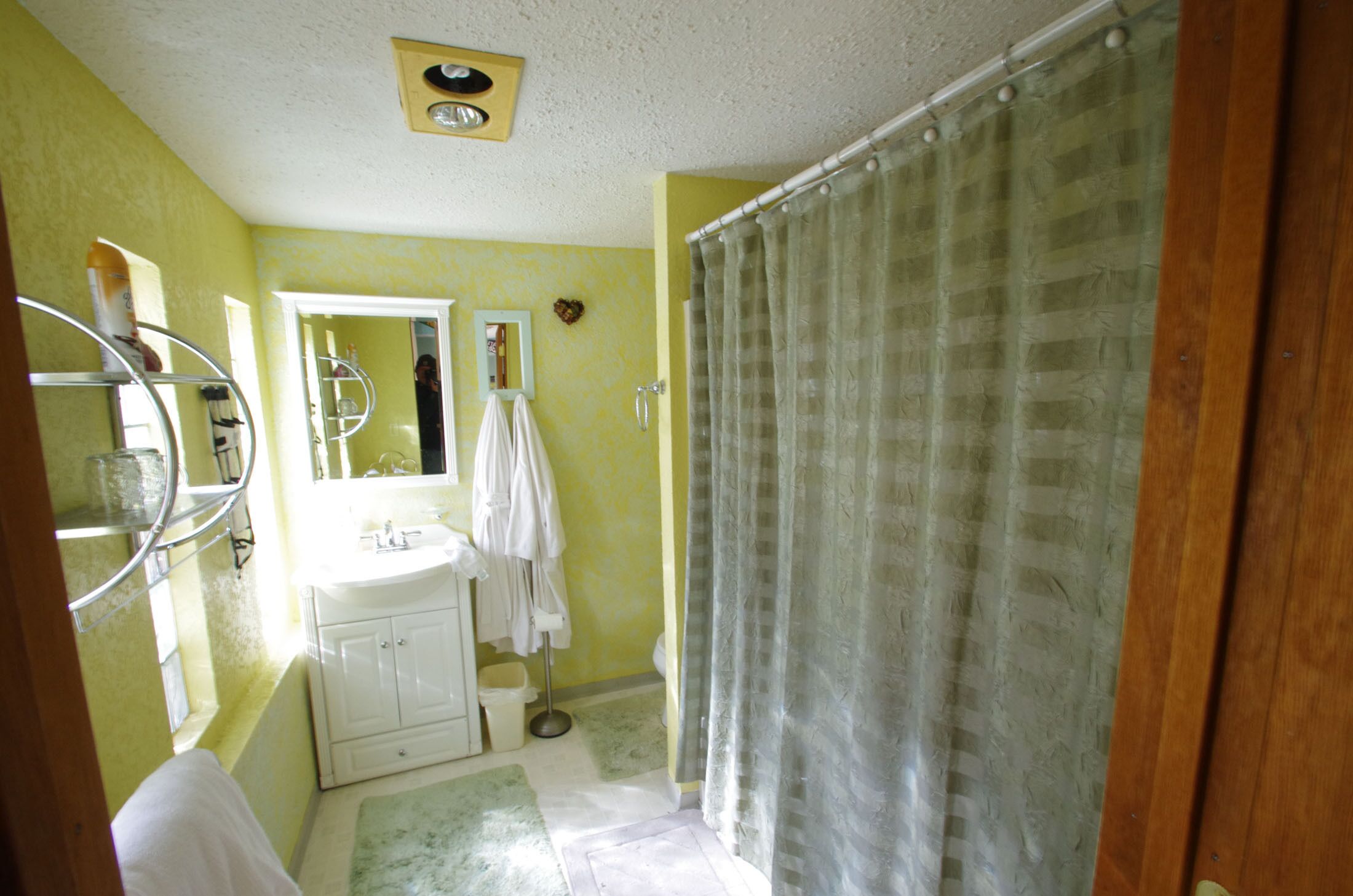 A bathroom with a white sink, mirror, and shower curtain.