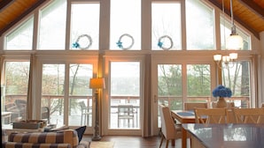A spacious room with large windows, a dining area, and a cozy seating area. - Beach Front on Beautiful Jenkins Pond, Quiet Area, 
Discounted off season rates! (East Falmouth)