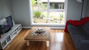 A living room with a wooden coffee table, a grey sofa, and a TV on a white stand.