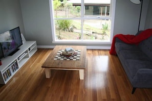 A living room with a wooden coffee table, a grey sofa, and a TV on a white stand. - Lorne Surfdogz at Lorne (Lorne)