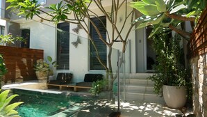 Ein moderner Poolbereich im Freien mit Glasveranda, umgeben von Kübelpflanzen und einer Holzterrasse.