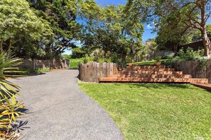 A paved driveway leading to a wooden fence with steps.