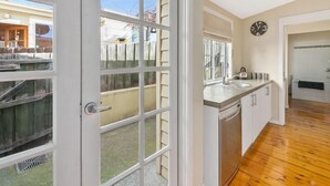 A modern kitchen with a large window, wooden flooring, and a clock on the wall.