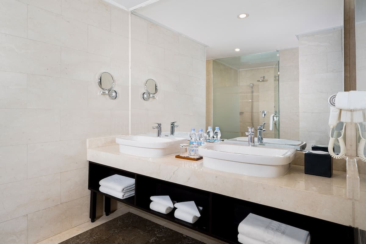 Une salle de bain moderne avec deux lavabos, un grand miroir et un sèche-cheveux sur le côté droit.